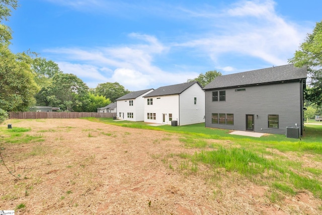 rear view of property with a yard, central AC unit, and a patio area