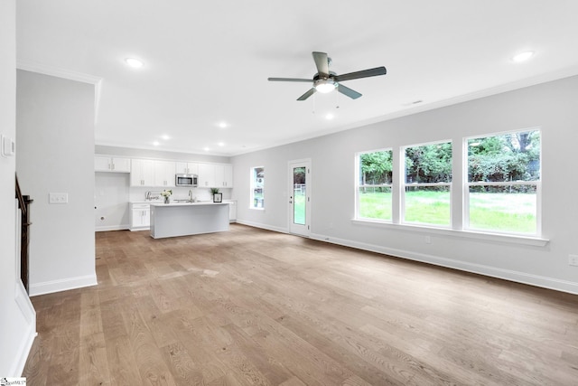 unfurnished living room featuring sink, ornamental molding, ceiling fan, and light wood-type flooring