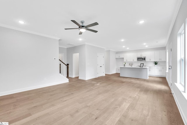 unfurnished living room with crown molding, ceiling fan, and light hardwood / wood-style floors