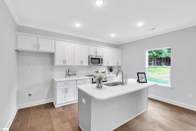 kitchen featuring a center island with sink, white cabinets, stainless steel appliances, wood-type flooring, and sink