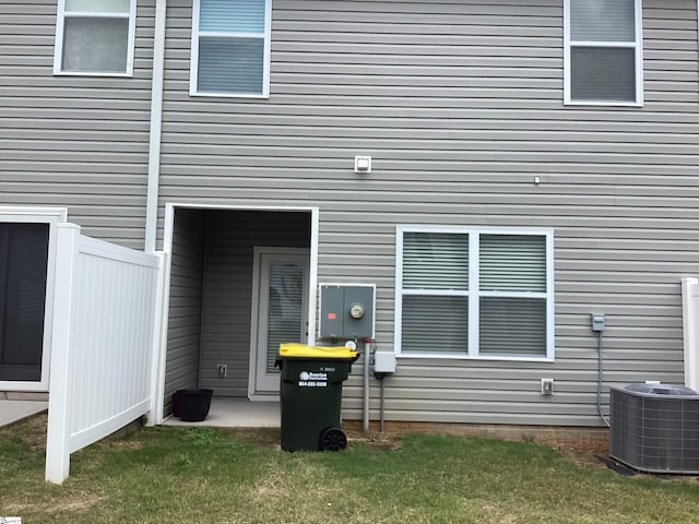 property entrance with central air condition unit and a lawn