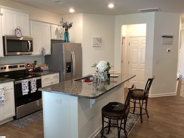 kitchen with white cabinetry, stainless steel appliances, dark hardwood / wood-style flooring, and an island with sink