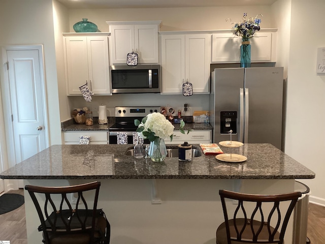 kitchen with a kitchen island, stainless steel appliances, light hardwood / wood-style floors, and a breakfast bar