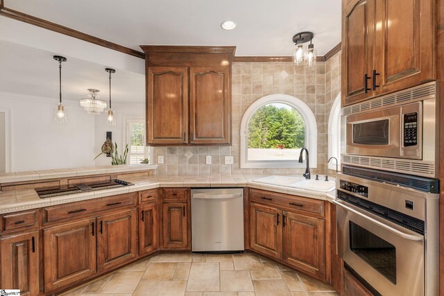 kitchen featuring a kitchen bar, stainless steel appliances, pendant lighting, light tile patterned flooring, and a notable chandelier