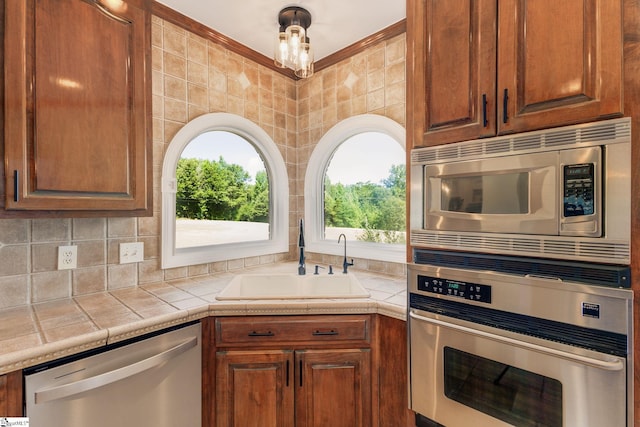 kitchen featuring tasteful backsplash, sink, tile counters, and appliances with stainless steel finishes