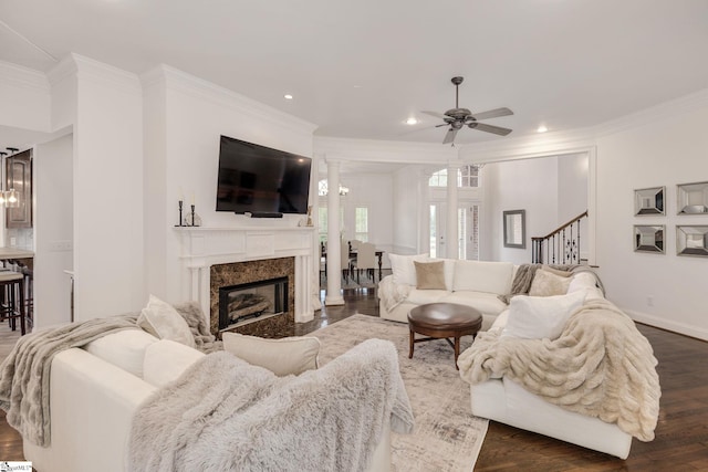 living room with decorative columns, crown molding, dark wood-type flooring, and ceiling fan