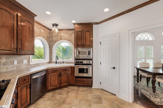 kitchen with appliances with stainless steel finishes, sink, backsplash, light tile patterned floors, and a notable chandelier