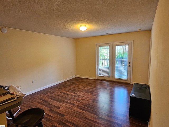 unfurnished room with a textured ceiling and dark wood-type flooring