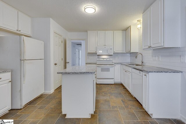 kitchen with white dishwasher, sink, backsplash, decorative light fixtures, and white cabinetry