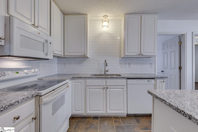 kitchen featuring dark tile patterned floors, white appliances, white cabinets, a kitchen island, and decorative backsplash