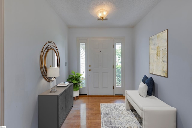 foyer entrance with light hardwood / wood-style flooring and a textured ceiling