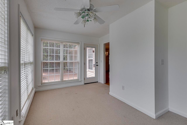 spare room featuring light colored carpet, a textured ceiling, and ceiling fan