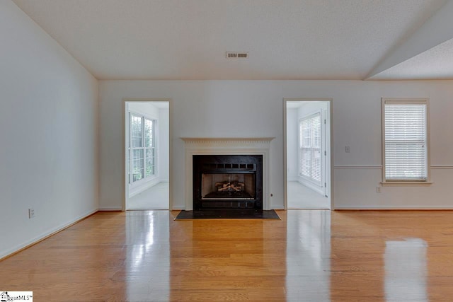 unfurnished living room featuring vaulted ceiling and light wood-type flooring