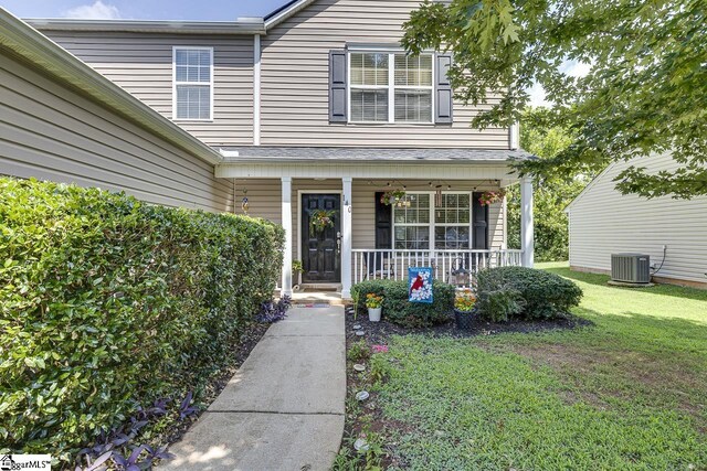 doorway to property with covered porch, a lawn, and central air condition unit