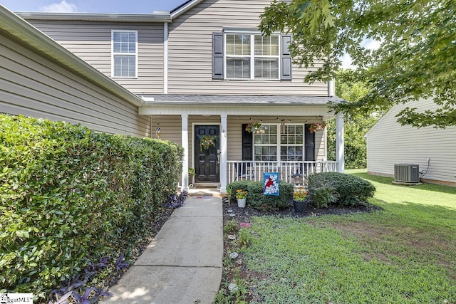 entrance to property with central air condition unit, a porch, and a lawn