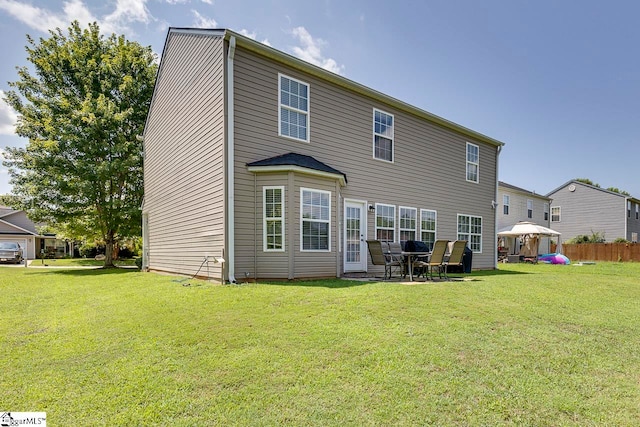 back of property with a yard and a patio