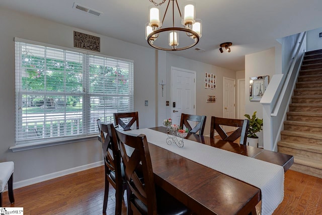 dining area with wood-type flooring and an inviting chandelier