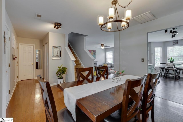 dining area featuring ceiling fan with notable chandelier, wood-type flooring, and plenty of natural light