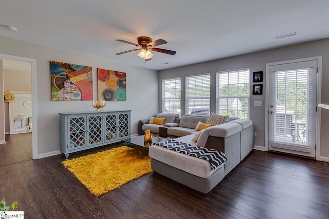 living room featuring a healthy amount of sunlight, ceiling fan, and dark wood-type flooring