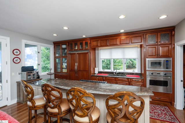 kitchen featuring a wealth of natural light, wood finished floors, a sink, and built in appliances