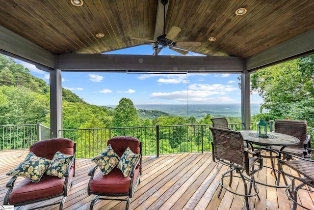 deck with a forest view and a ceiling fan