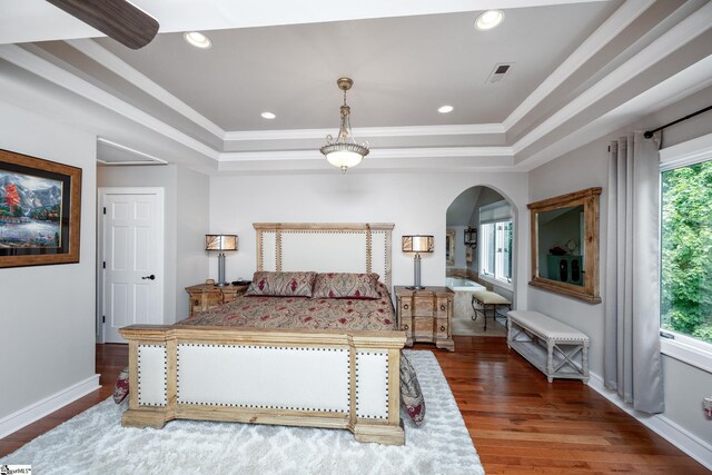 bedroom with crown molding, dark wood-type flooring, a raised ceiling, and multiple windows