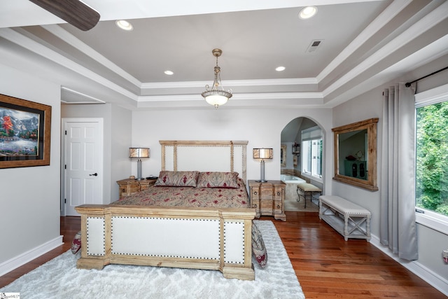 bedroom featuring arched walkways, wood finished floors, visible vents, ornamental molding, and a tray ceiling