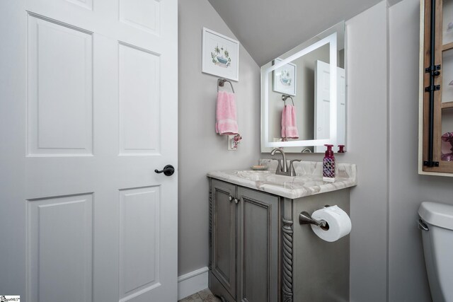 bathroom with vanity, lofted ceiling, and toilet