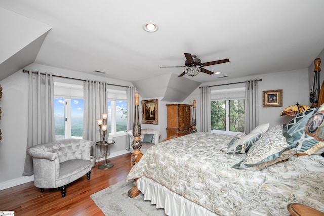 bedroom with lofted ceiling, ceiling fan, wood finished floors, visible vents, and baseboards