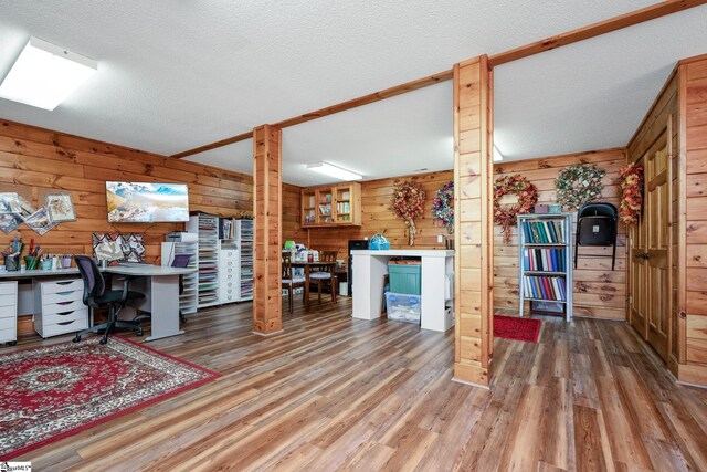 office featuring hardwood / wood-style floors, wooden walls, and a textured ceiling