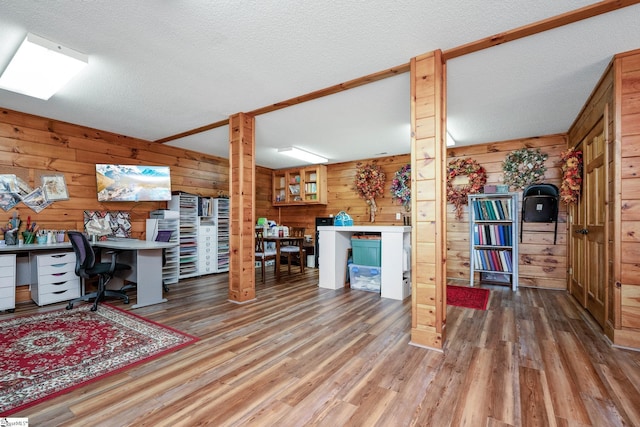 office area with wood walls, a textured ceiling, and wood finished floors