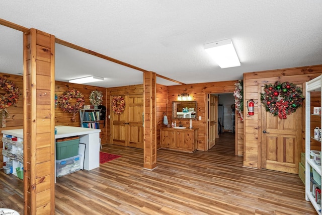 kitchen featuring a textured ceiling, light wood-style flooring, and wooden walls