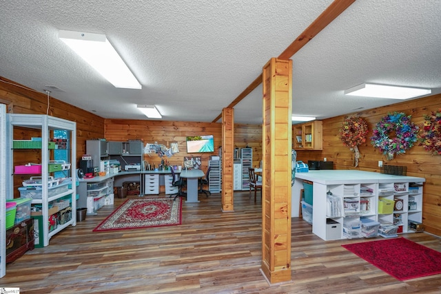 kitchen with a textured ceiling, wooden walls, and wood finished floors