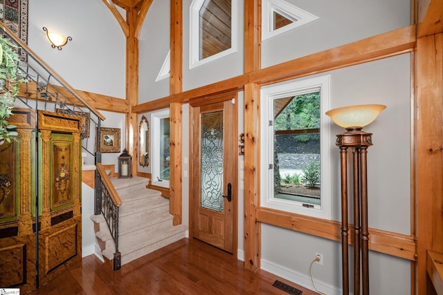 foyer entrance with visible vents, a high ceiling, dark wood-type flooring, baseboards, and stairs