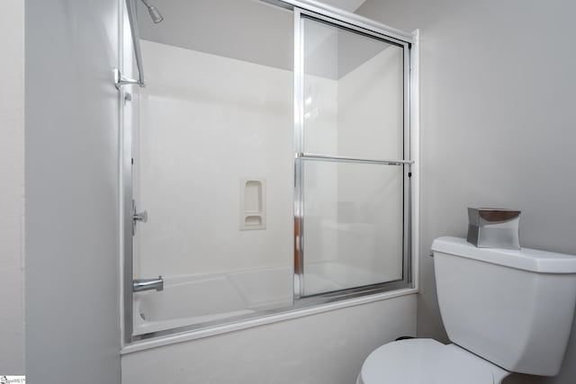 full bath with toilet and shower / bath combination with glass door