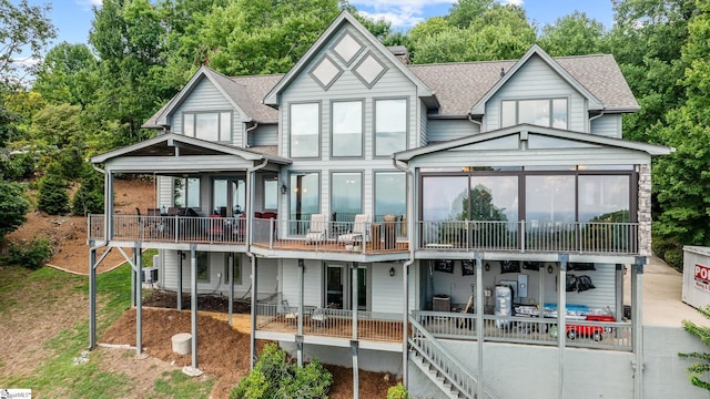 exterior space featuring a deck, a shingled roof, a chimney, and a patio area