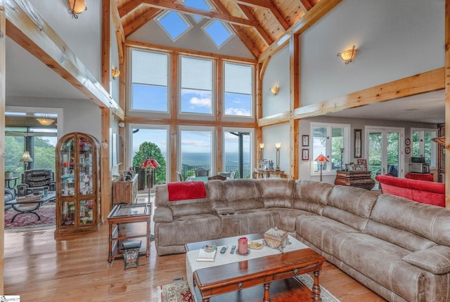 living room with a wealth of natural light, beamed ceiling, and light wood-style flooring