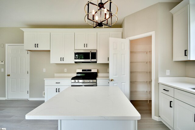 kitchen with light stone counters, a center island, hanging light fixtures, appliances with stainless steel finishes, and white cabinets