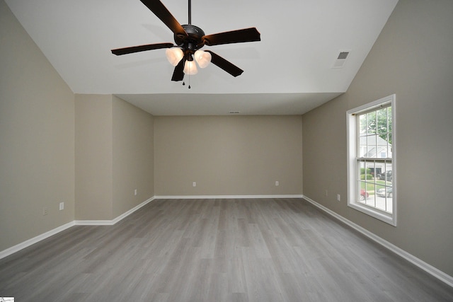 empty room featuring vaulted ceiling, light hardwood / wood-style floors, and ceiling fan