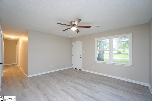 spare room featuring ceiling fan, light hardwood / wood-style floors, and a textured ceiling