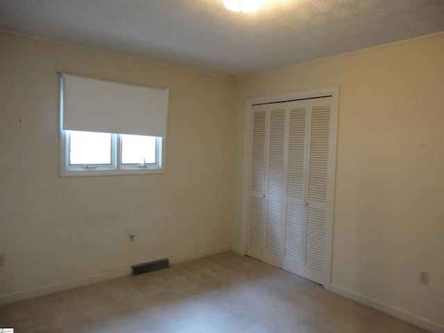 unfurnished bedroom featuring light carpet, crown molding, and a closet