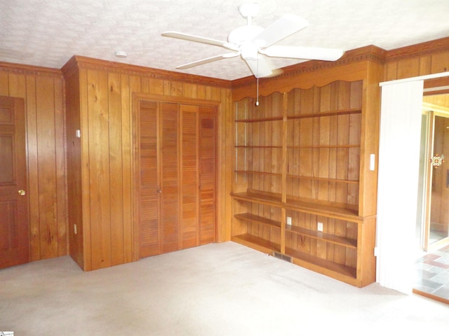 carpeted bedroom featuring ceiling fan, wooden walls, and a closet