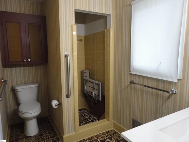 bathroom featuring sink, a tile shower, and toilet