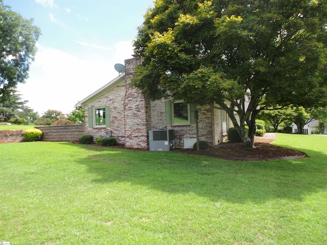 view of side of home with a yard and central AC