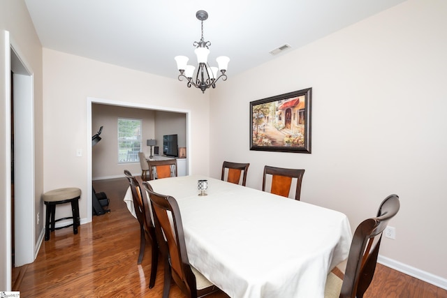 dining space with dark hardwood / wood-style flooring and a chandelier