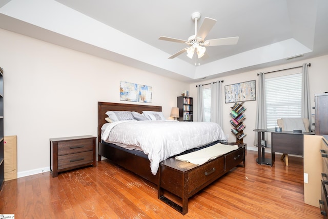 bedroom featuring hardwood / wood-style flooring, ceiling fan, and a raised ceiling