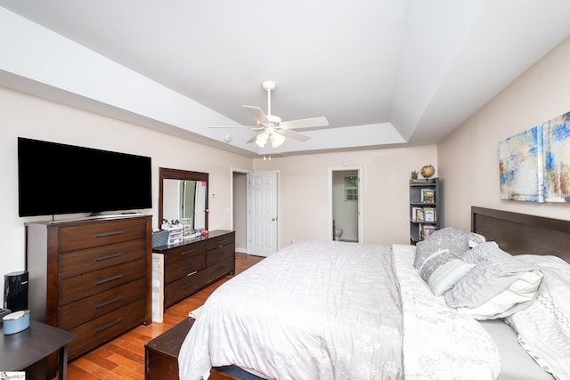 bedroom with wood-type flooring, a raised ceiling, and ceiling fan