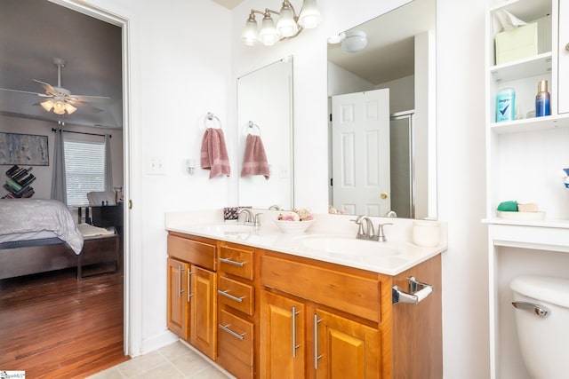 bathroom featuring hardwood / wood-style flooring, a shower with door, ceiling fan, vanity, and toilet