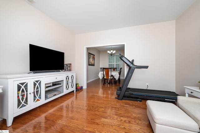 workout area featuring hardwood / wood-style floors and a notable chandelier