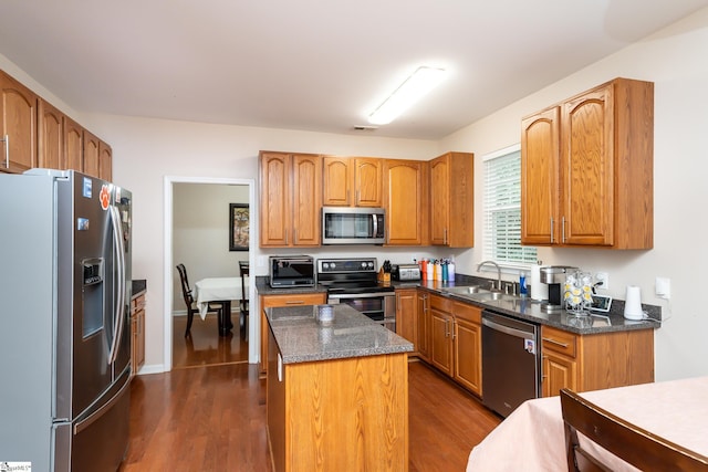 kitchen featuring sink, dark wood-type flooring, a center island, and appliances with stainless steel finishes